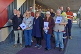 A group of people facing the camera holding reports