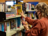 Person putting book on shelf with books on it